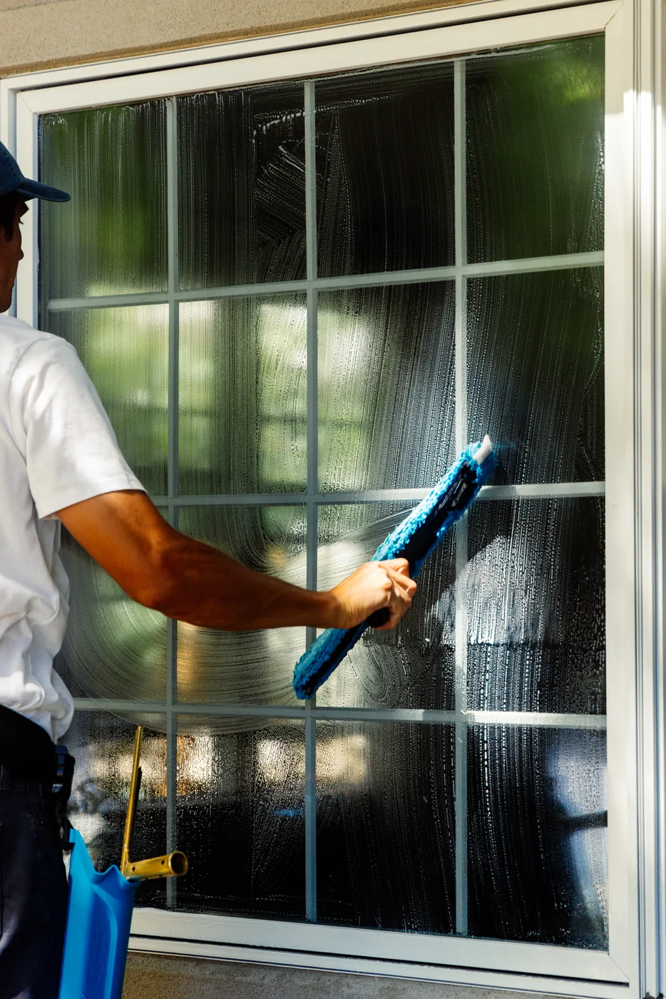 Technician cleaning a divided-lite window, visible through the streak-free glass