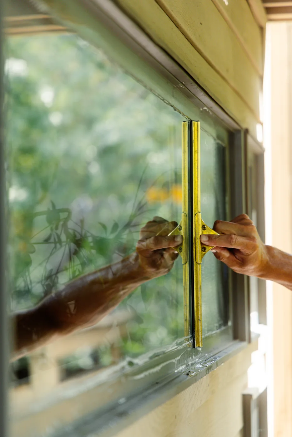 Close-up of a squeegee clearing a clean, streak-free path across a window pane